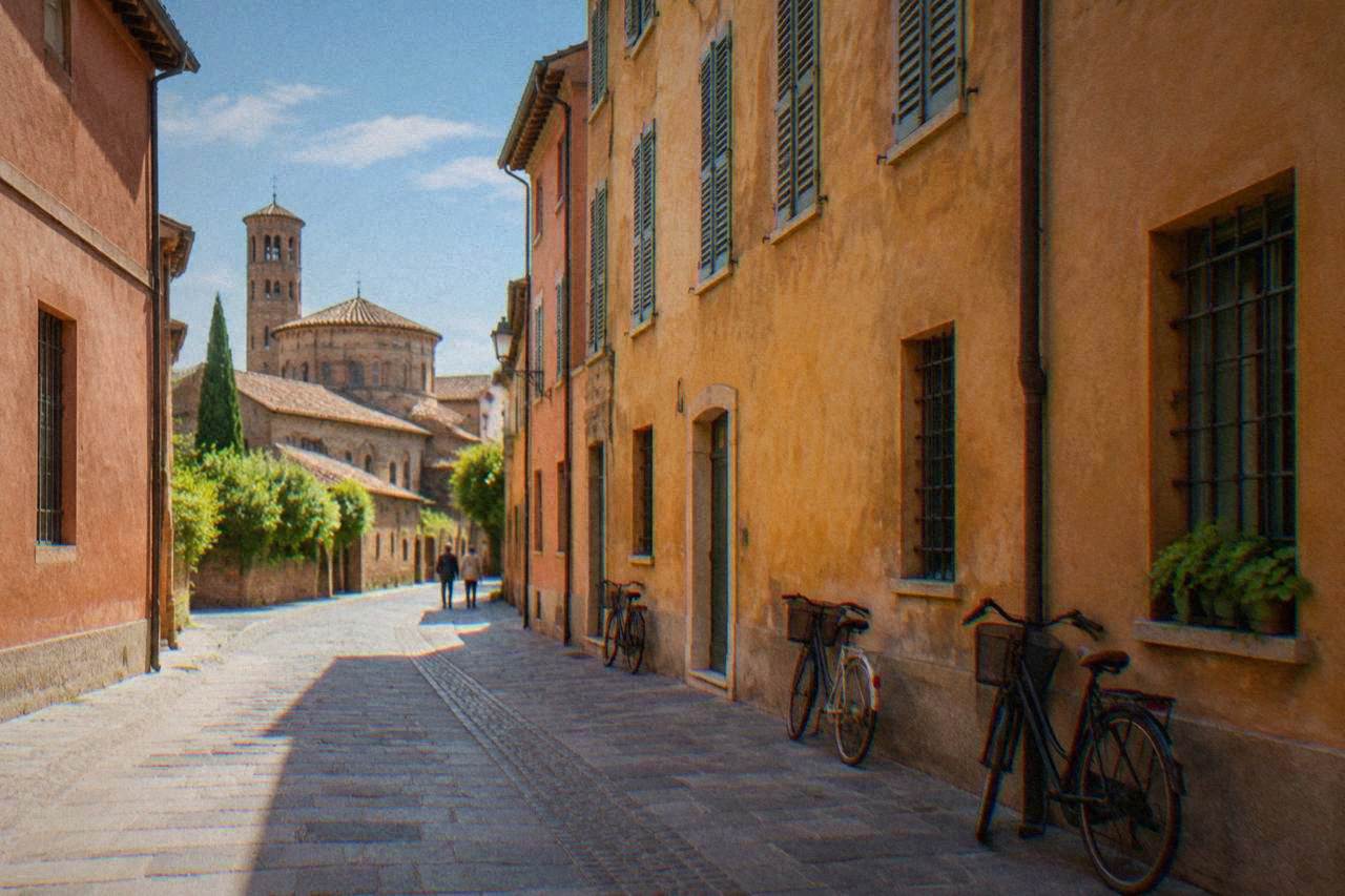A quiet cobbled street in central Ravenna lined with low brick buildings and bicycles