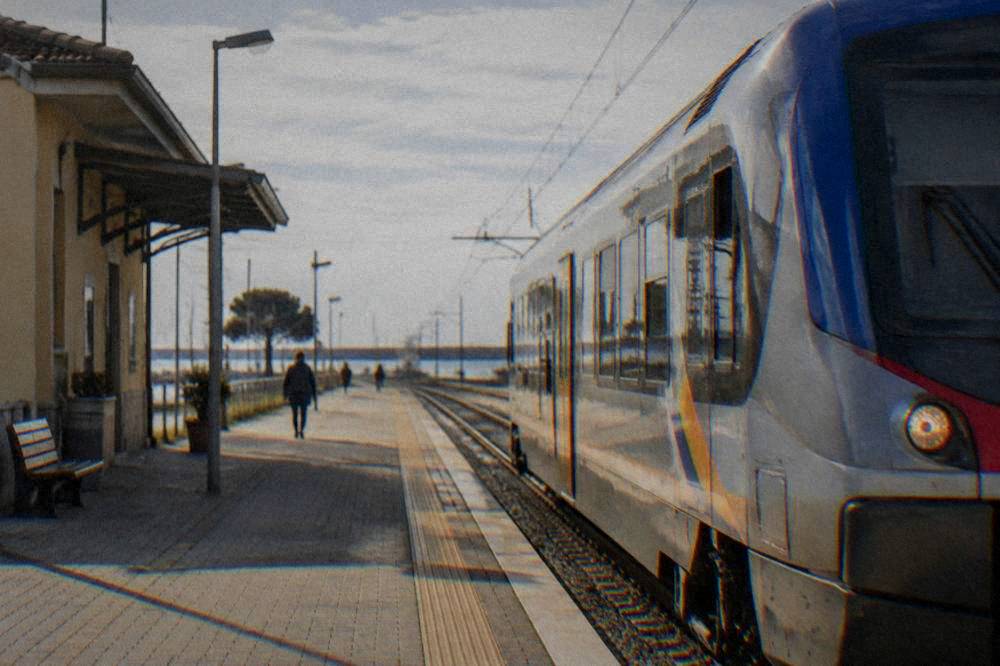 Regional train at a platform of a small Italian railway station in morning light