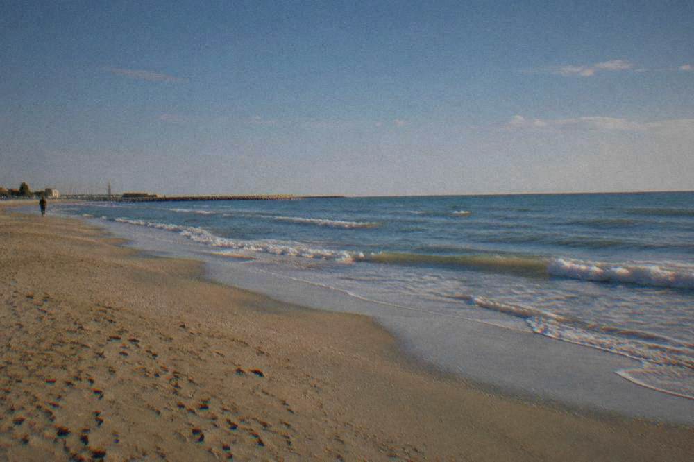 Empty golden beach in late afternoon light with gentle waves along the shore