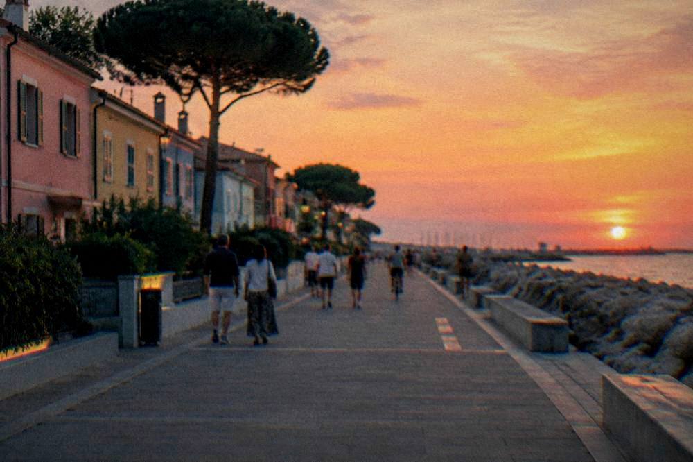 Seaside promenade with pastel buildings and people strolling in the evening