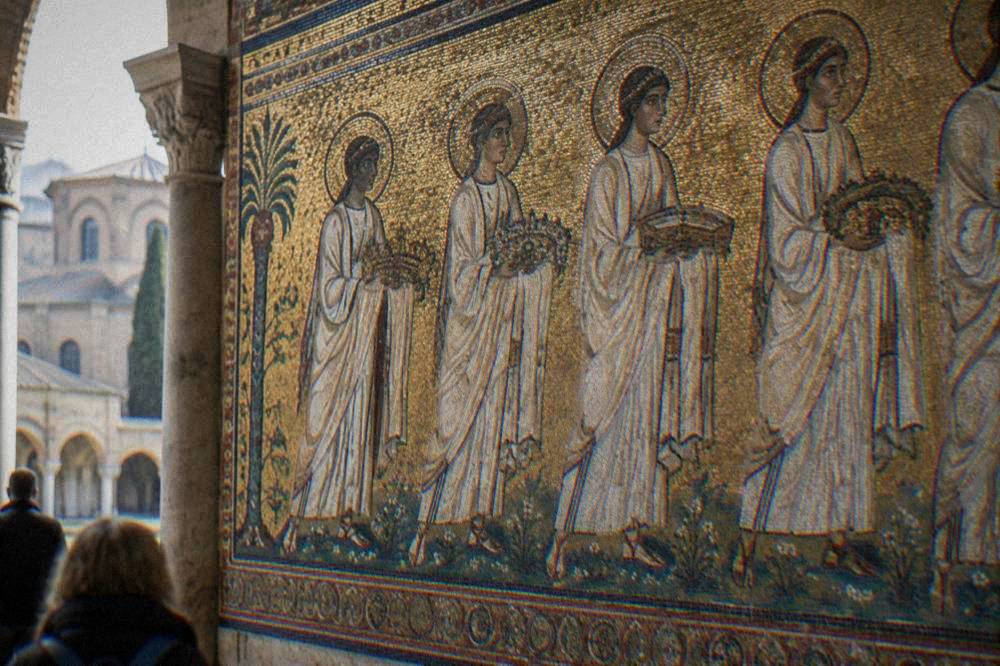 Close view of a gold Byzantine mosaic wall with a procession of white-robed figures holding crowns