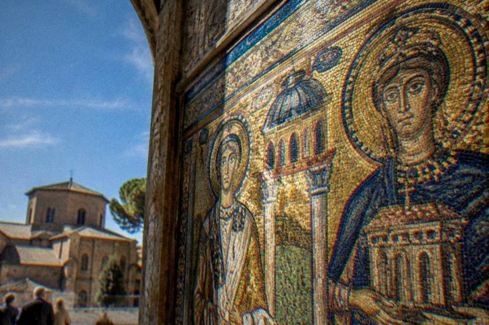 A detailed view of gold glass tesserae mosaic depicting figures and architectural patterns in Ravenna
