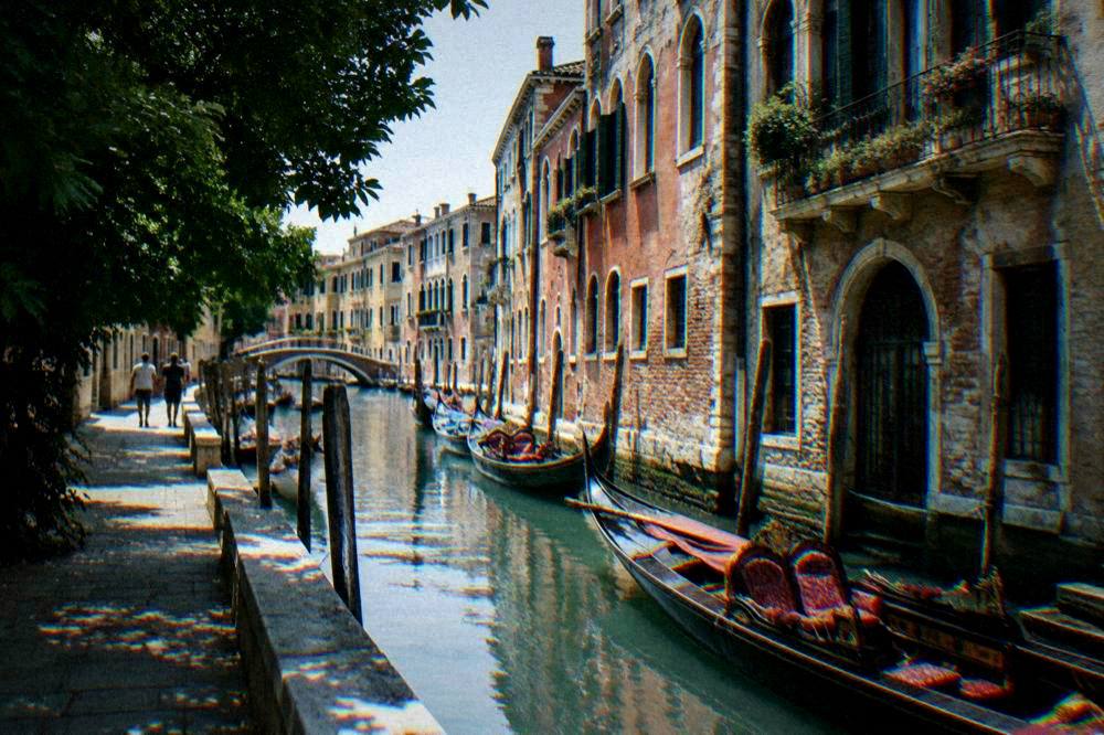 Gondolas moored along a narrow canal beside old Venetian palace facades