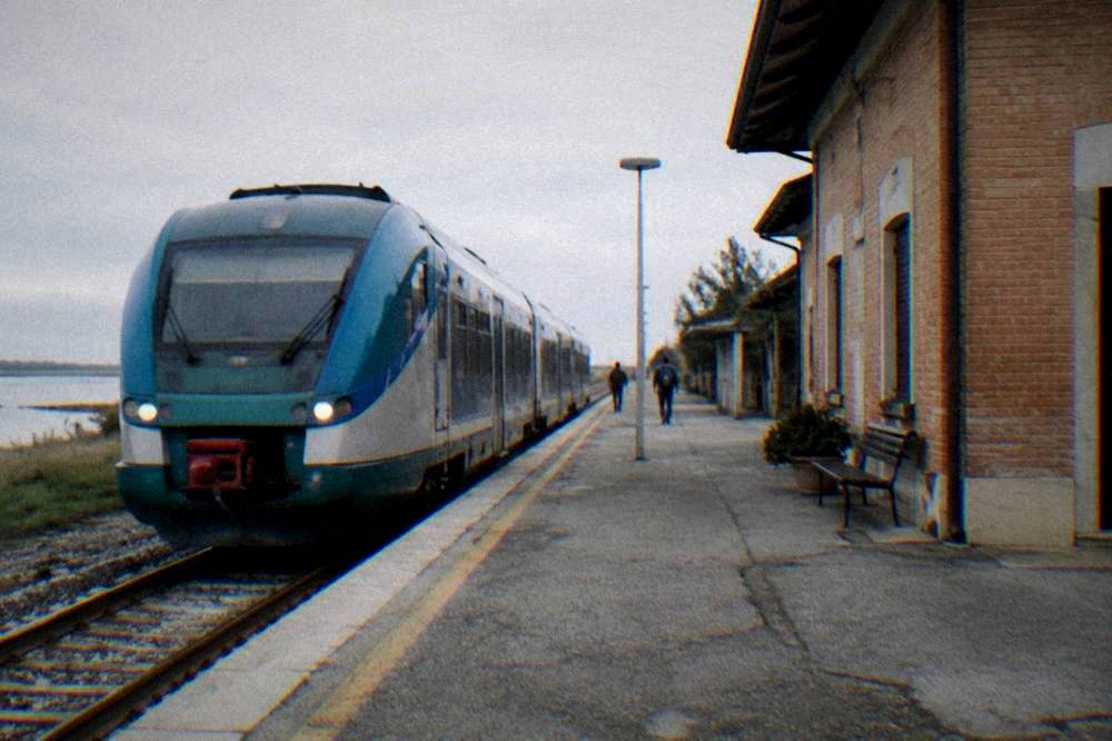 Regional train waiting at a small station platform beside a brick station building