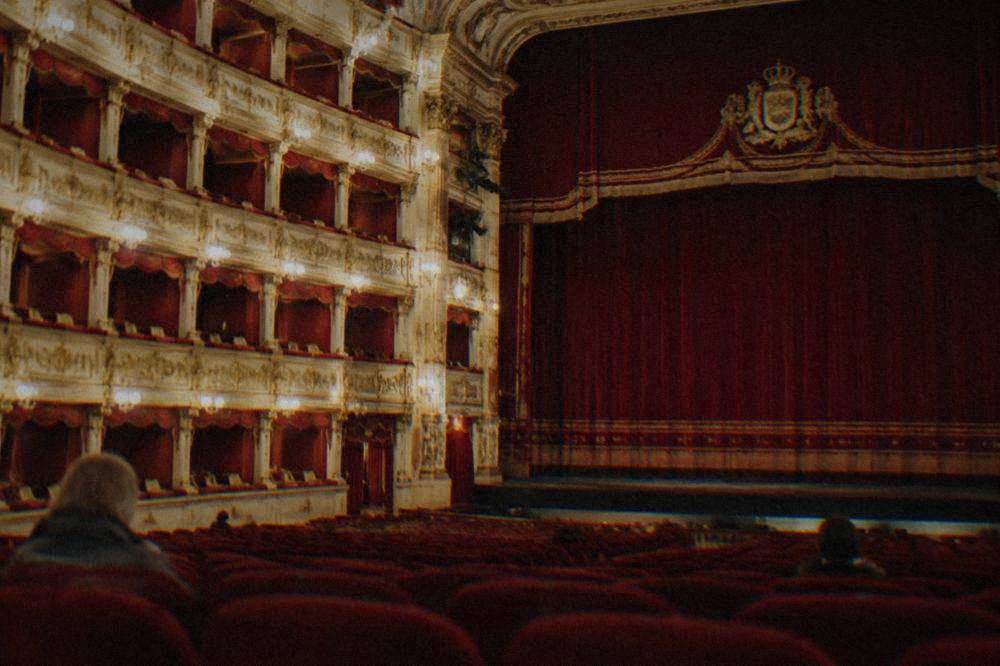 An ornate gilded opera house auditorium with red velvet seats and tiers of boxes