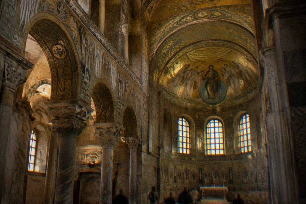 Interior of San Vitale in Ravenna with gold mosaic vaults glowing under dim light