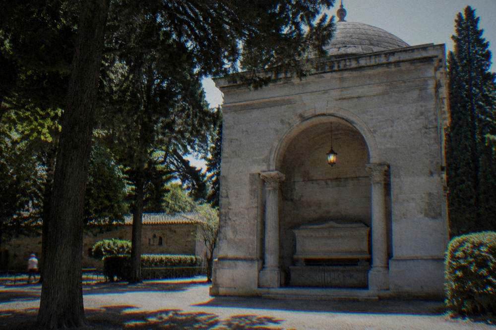 The plain stone exterior of Dante's tomb in Ravenna with a small lamp burning above the sarcophagus