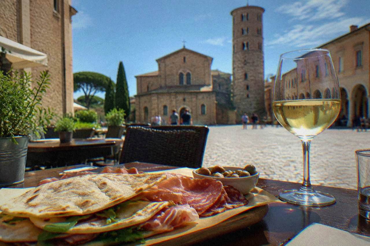 A table in a Ravenna eaterie with piadina bread, cured meats and a glass of white wine