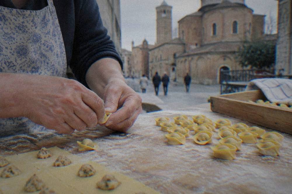 Hands rolling small cappelletti pasta parcels on a floured wooden board