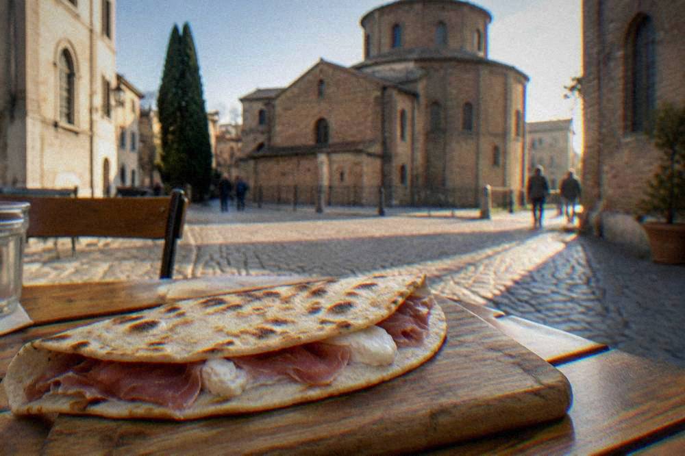A freshly cooked piadina folded over soft cheese and cured ham on a wooden board