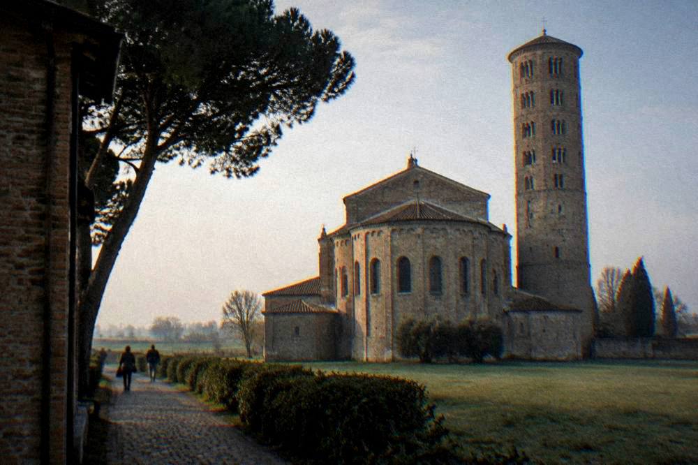 The tall brick apse and campanile of a basilica standing in flat open countryside