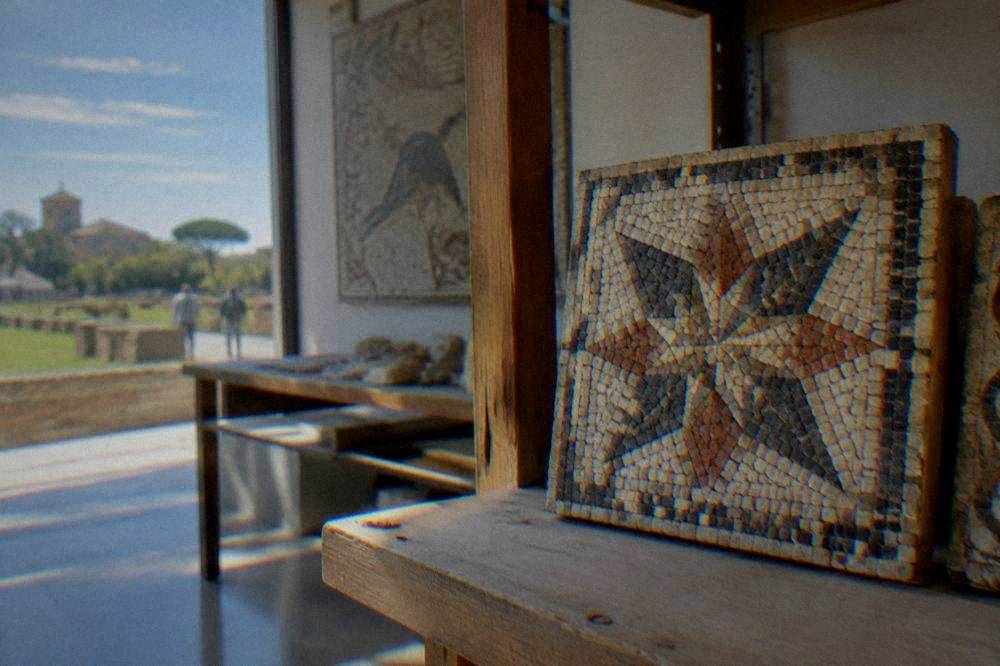 A finished small mosaic panel with a geometric star pattern resting on a studio shelf