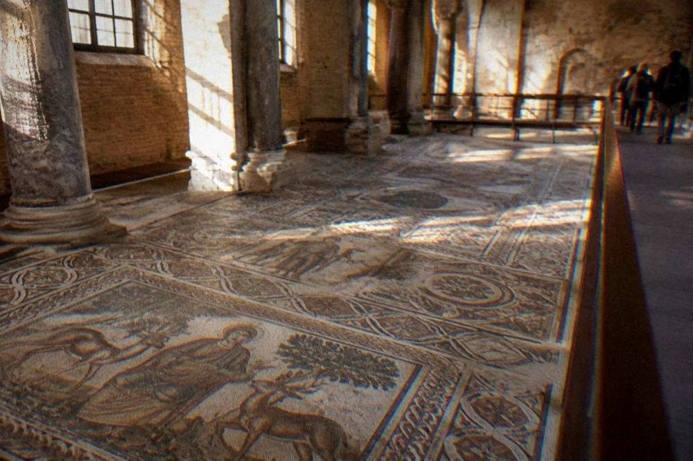 Byzantine mosaic floor with geometric and figural panels viewed from a walkway