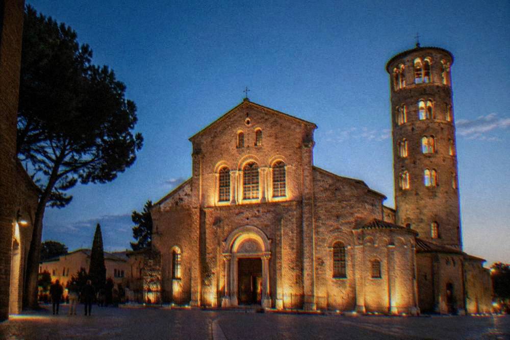A floodlit historic church facade in Ravenna seen after dark