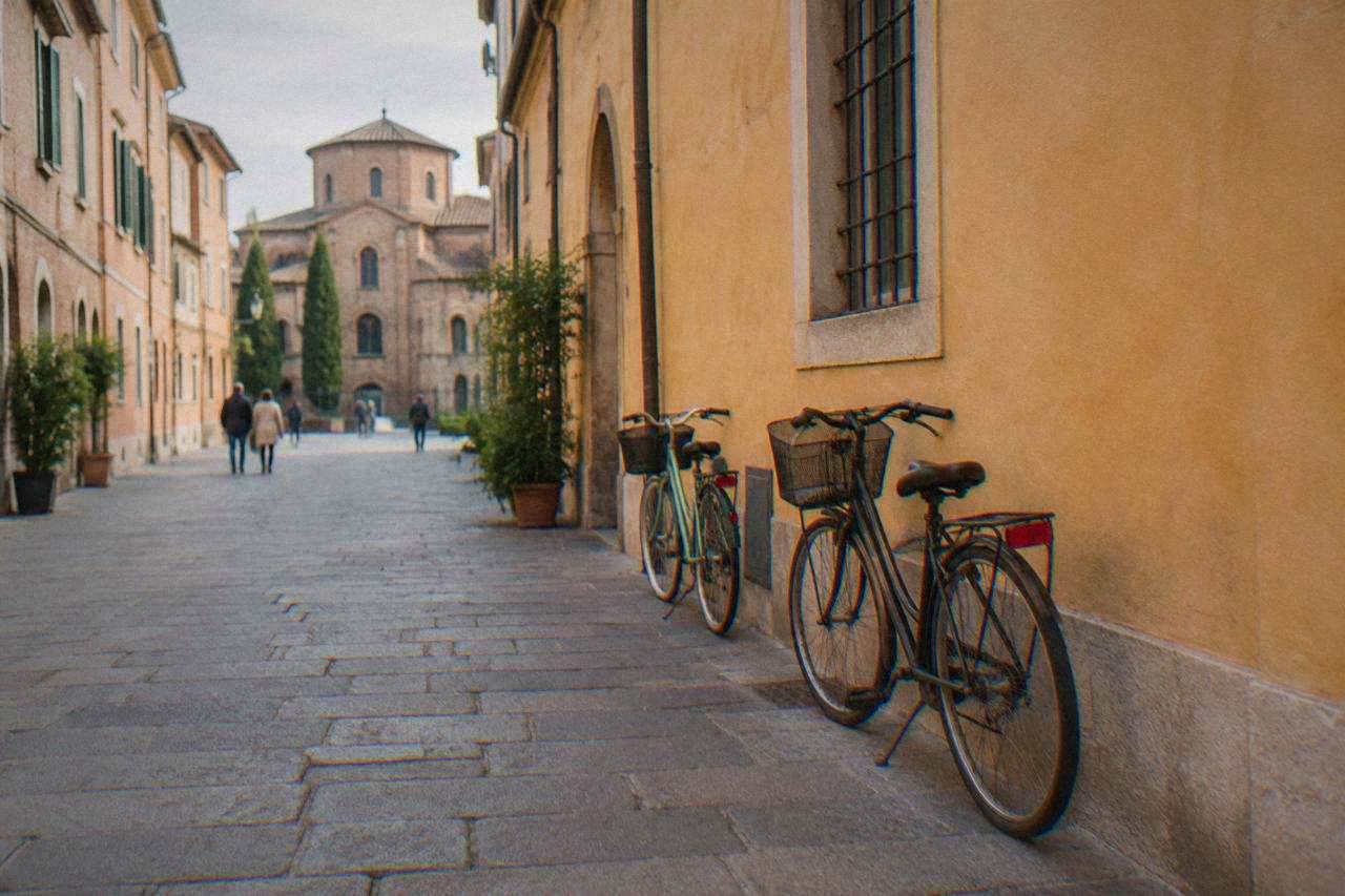 A quiet cobbled street in Ravenna's historic centre with old brick facades and a bicycle leaning against a wall