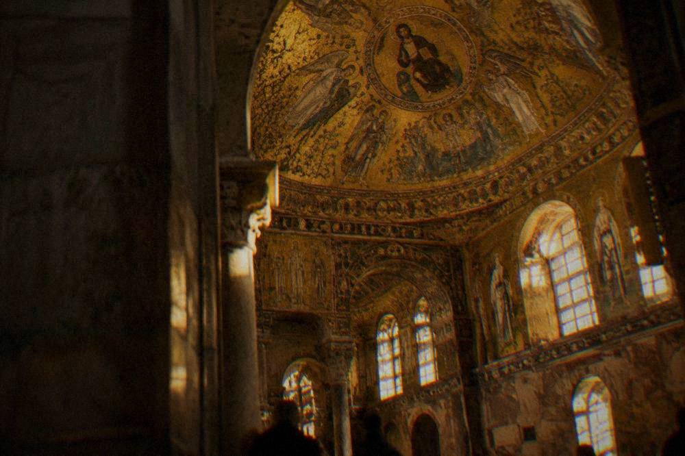 The brick exterior of a mosaic basilica in Ravenna seen from a narrow lane in morning light