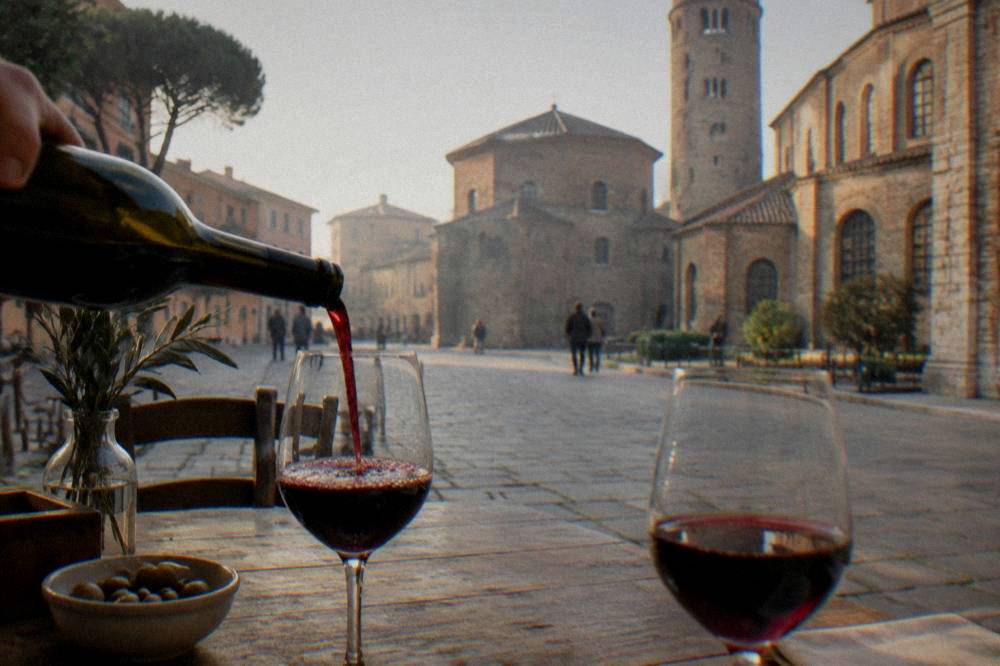 Red wine being poured into simple glasses on a wooden restaurant table