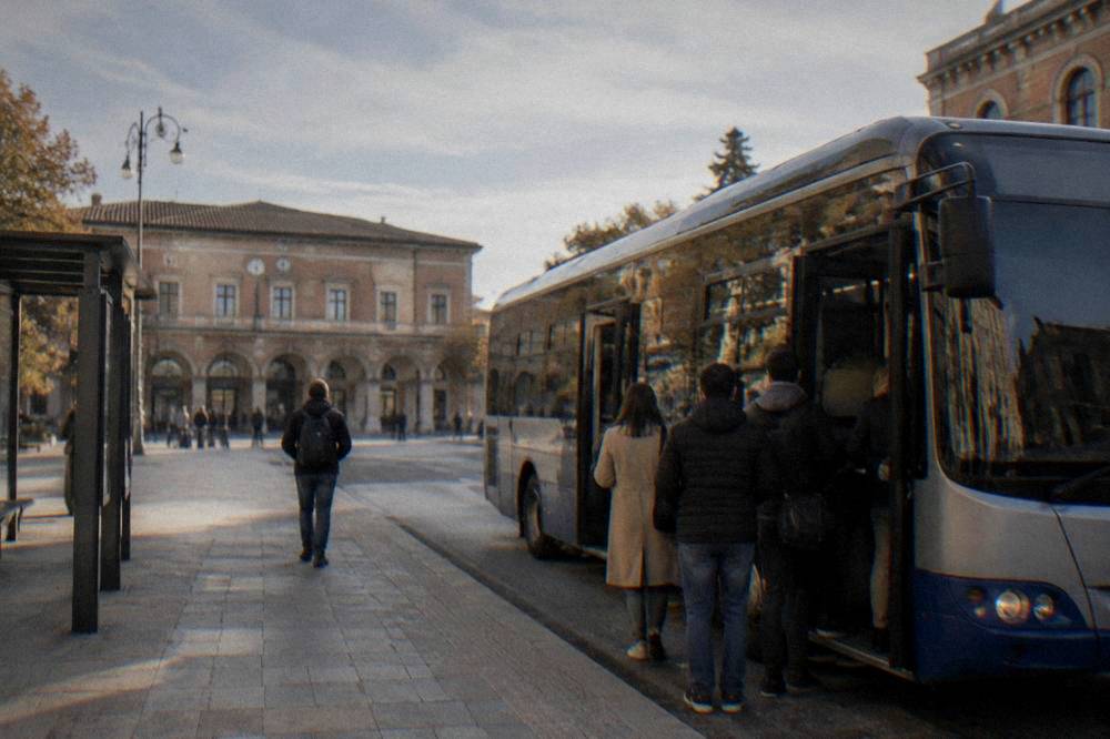 A bus waiting at a stop outside Ravenna station with passengers boarding