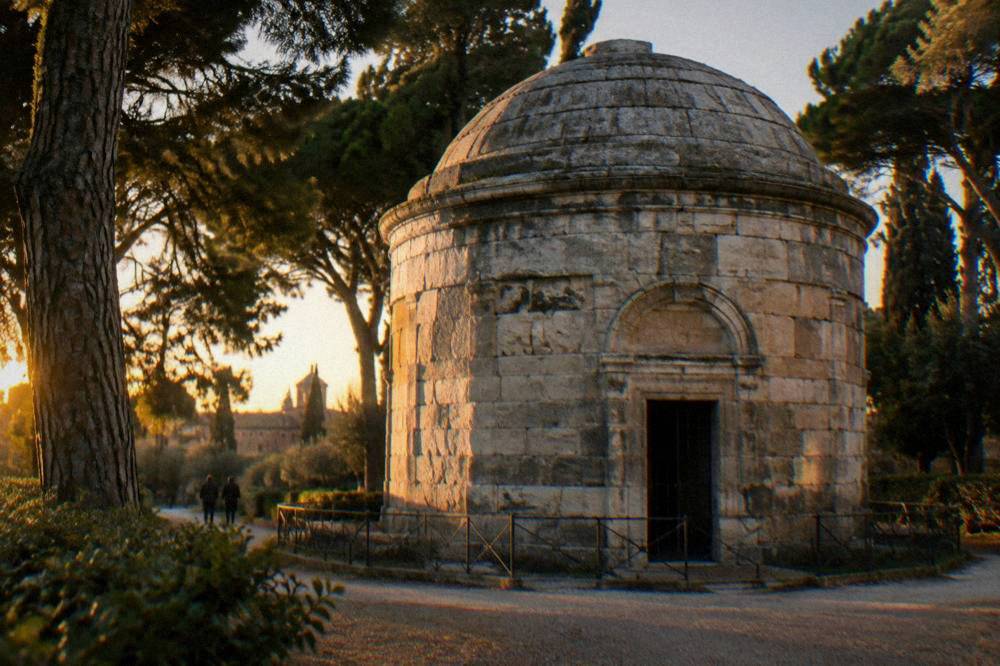 A stone mausoleum of ancient blocks with a shallow dome surrounded by trees