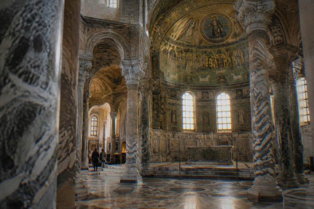 Interior of an octagonal church with richly patterned marble columns and mosaic sanctuary