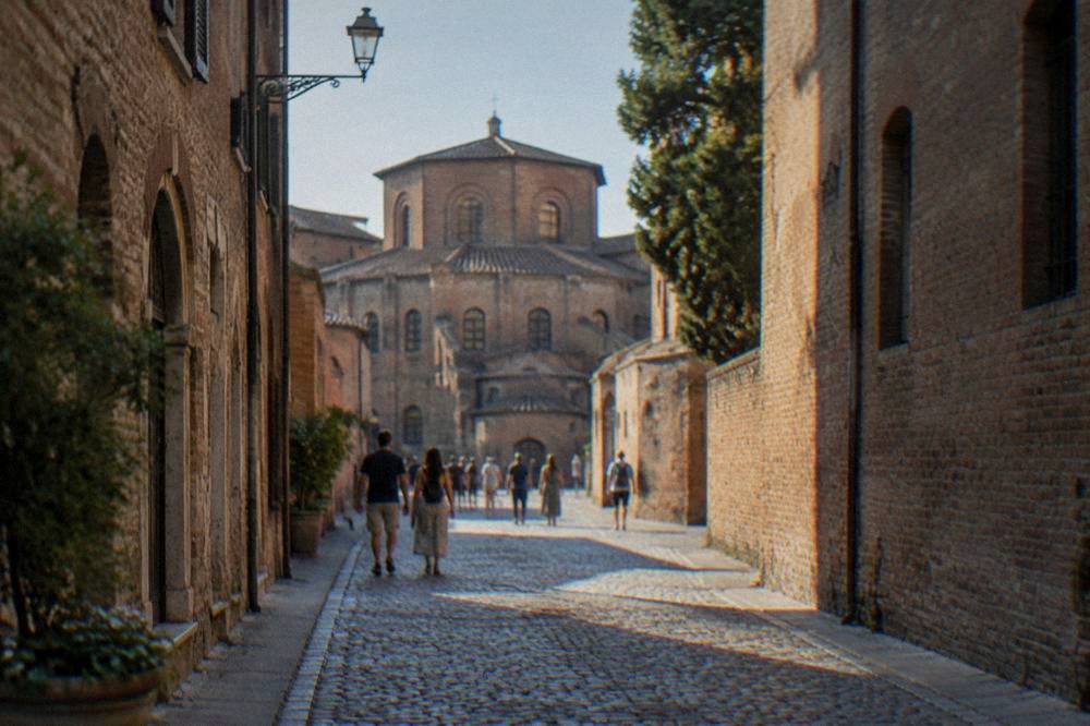 Tourists walking a narrow cobbled street lined with old brick buildings in Ravenna