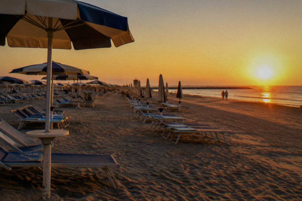 A wide sandy Adriatic beach with rows of sunbeds and umbrellas at a resort town
