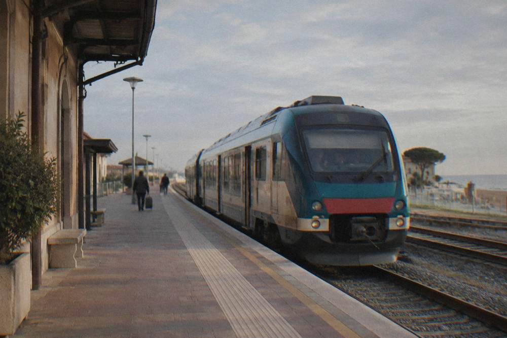 A regional train waiting at a small Italian railway station platform