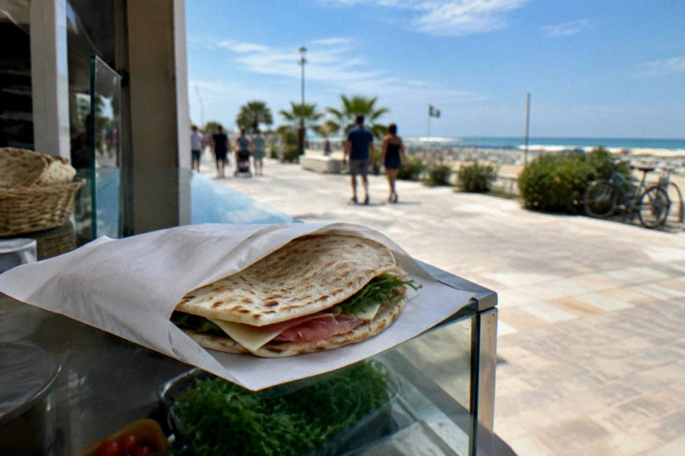 A thin Italian flatbread folded and wrapped in paper on a deli counter