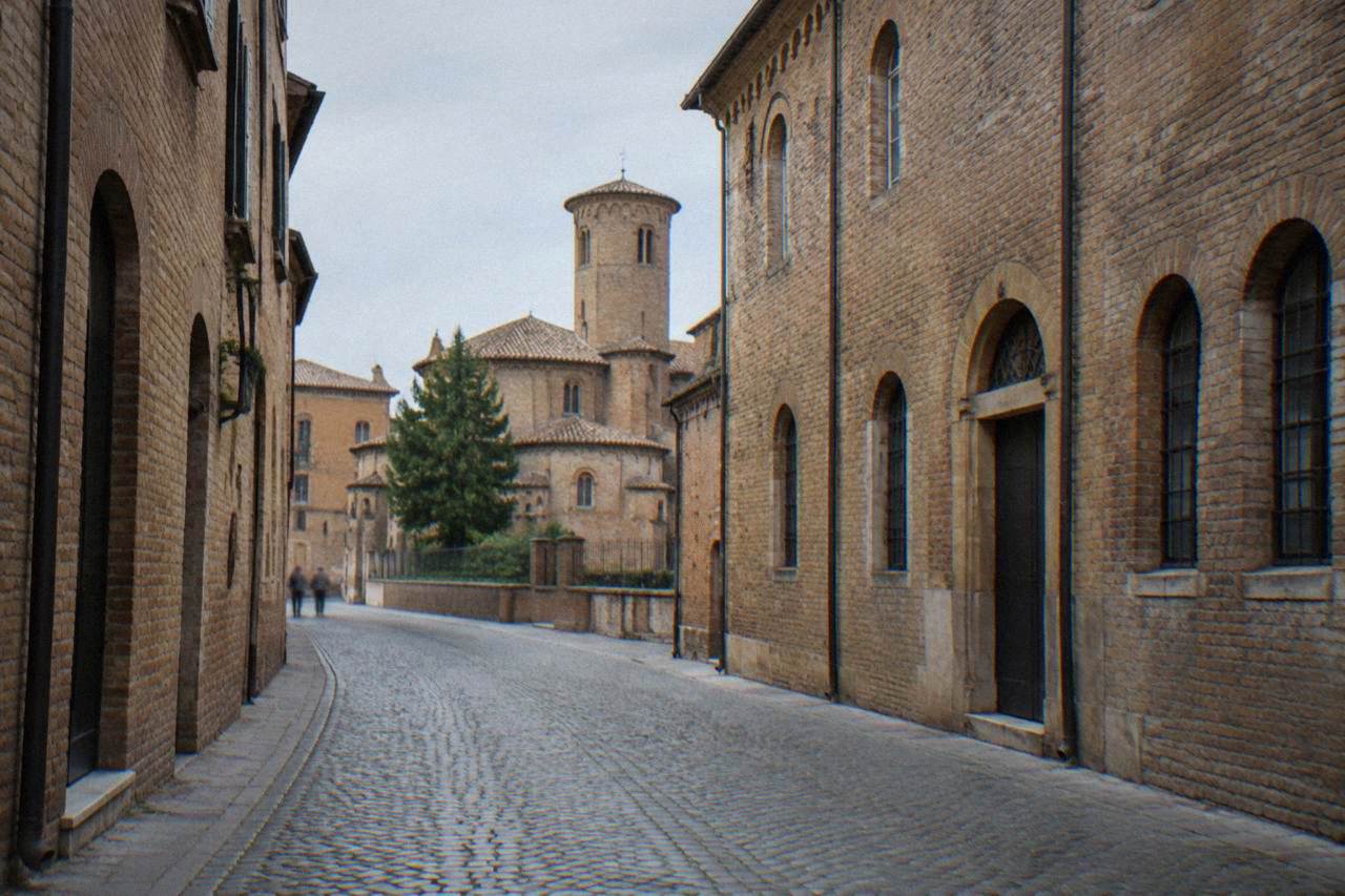 A quiet cobbled street in the historic centre of Ravenna under a soft morning sky