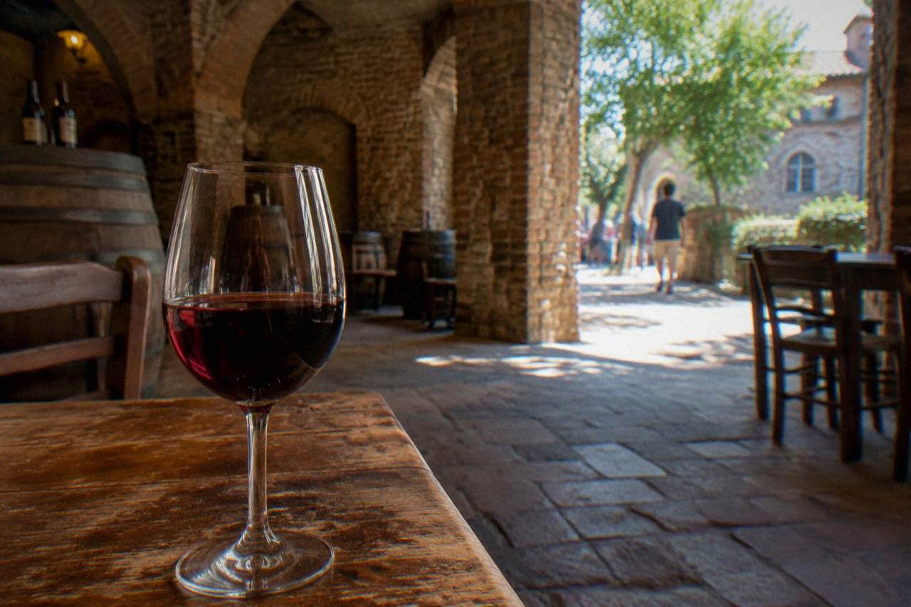 A glass of red wine on a wooden table in a rustic Italian cellar