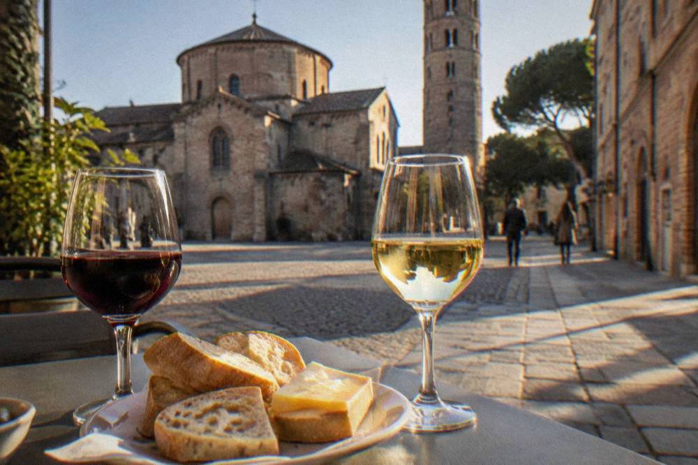 Two wine glasses, one red and one white, beside a plate of bread and cheese
