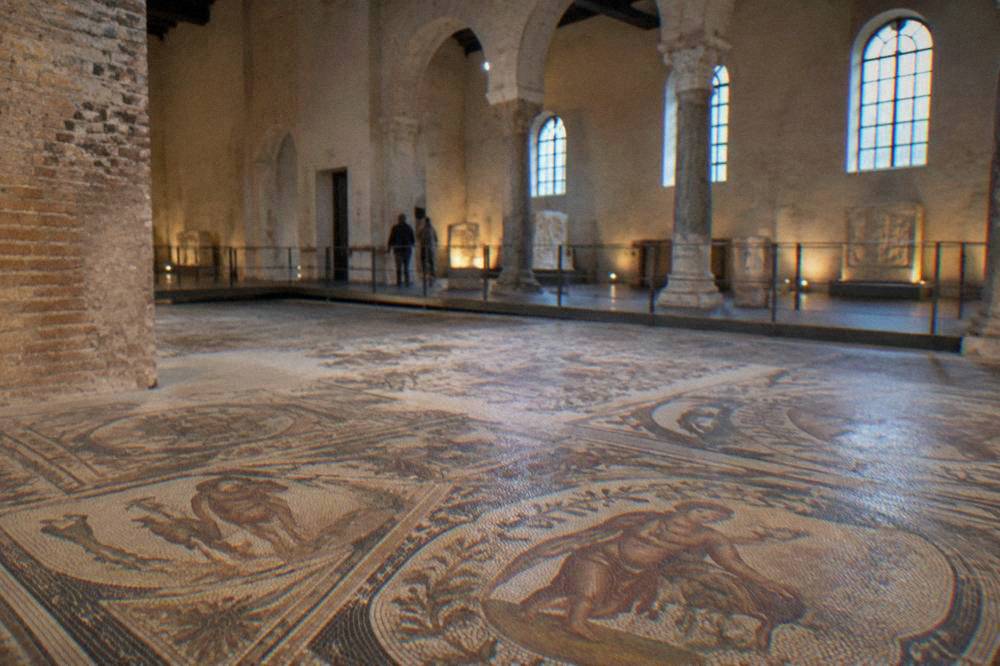 Interior of a museum hall with ancient mosaic floors and soft lighting