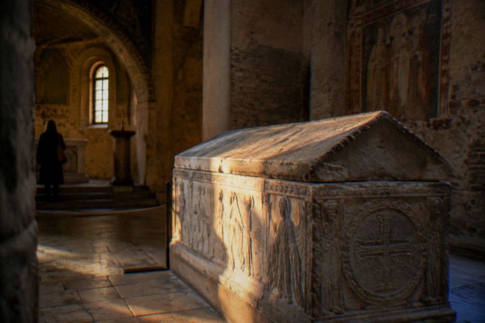 A stone sarcophagus and quiet interior of a small funerary chapel with soft natural light