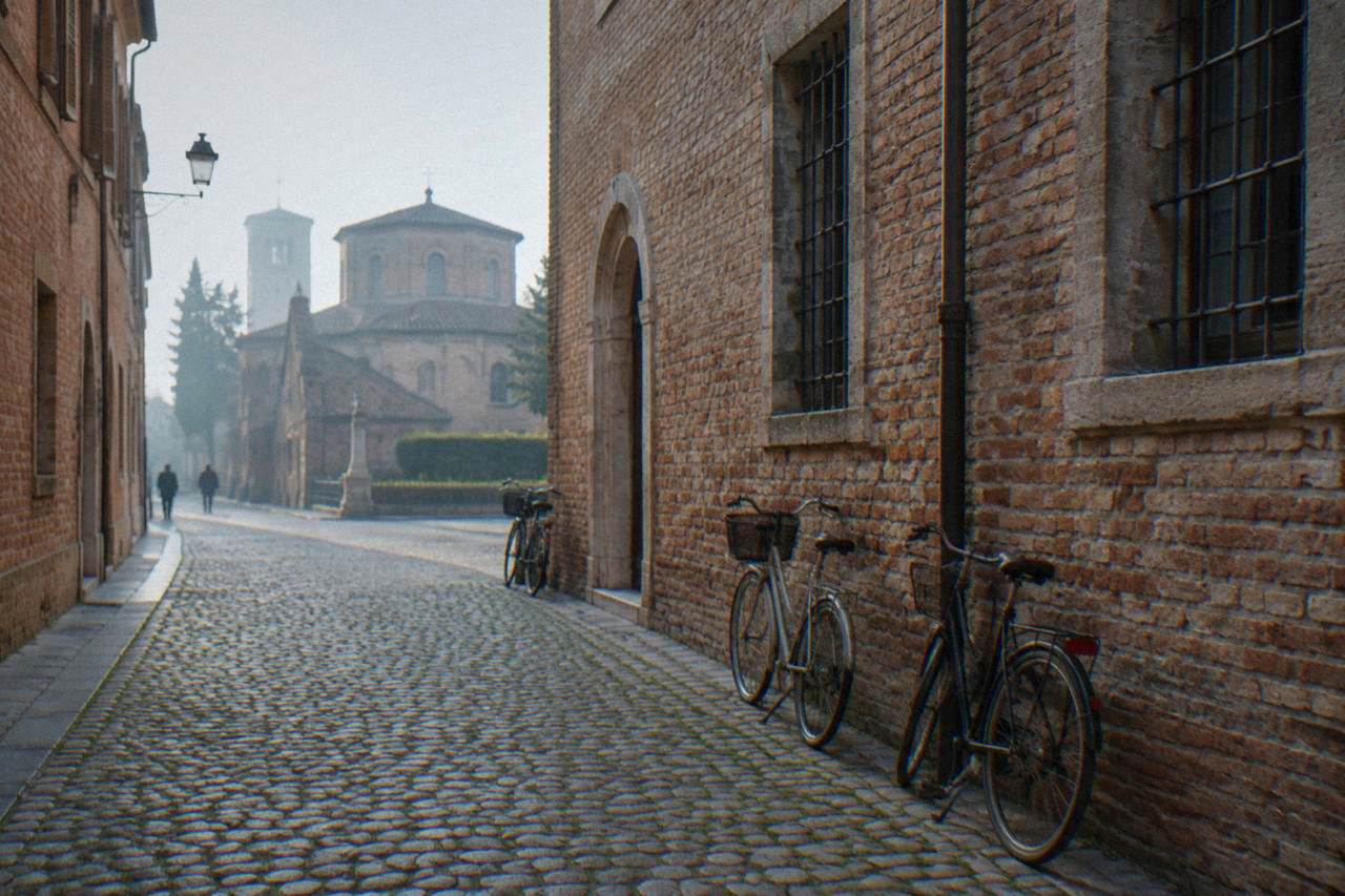 A quiet cobbled street in central Ravenna with old brick buildings and bicycles leaning against a wall