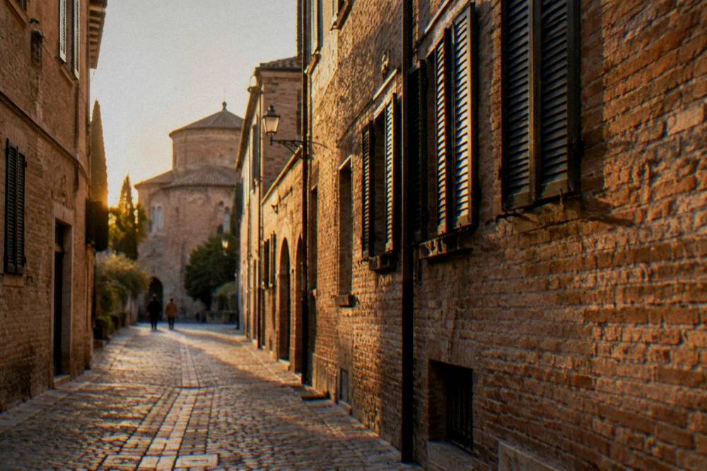 A narrow medieval lane in Ravenna lined with brick facades and shutters