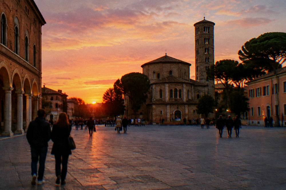 A wide pedestrian square in Ravenna at dusk with historic buildings and people strolling