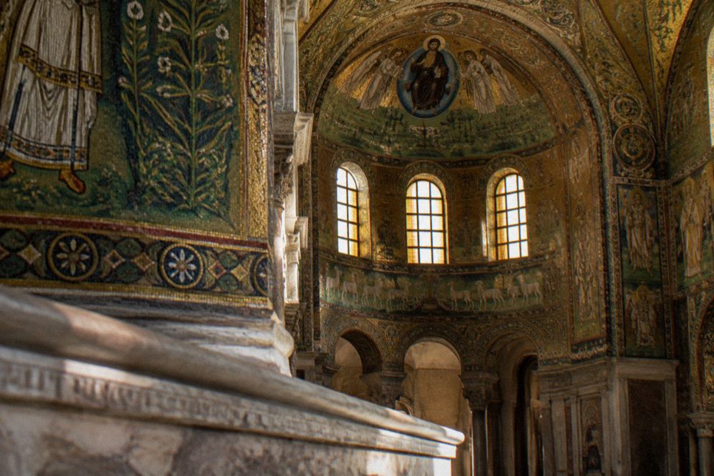 A row of tickets and a guidebook on a stone ledge inside a mosaic-lined church