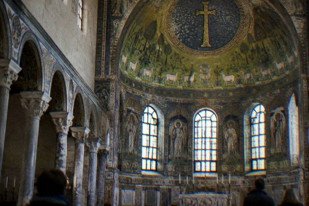Basilica apse with green mosaic fields and sheep above golden stars