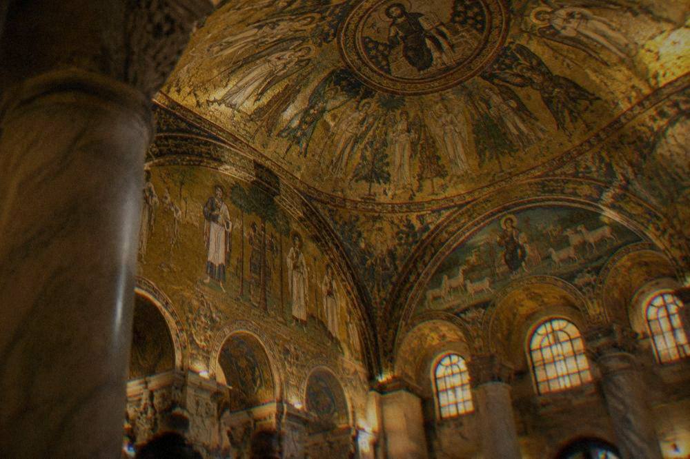 Golden mosaic ceiling inside a Ravenna monument lit by warm interior lighting