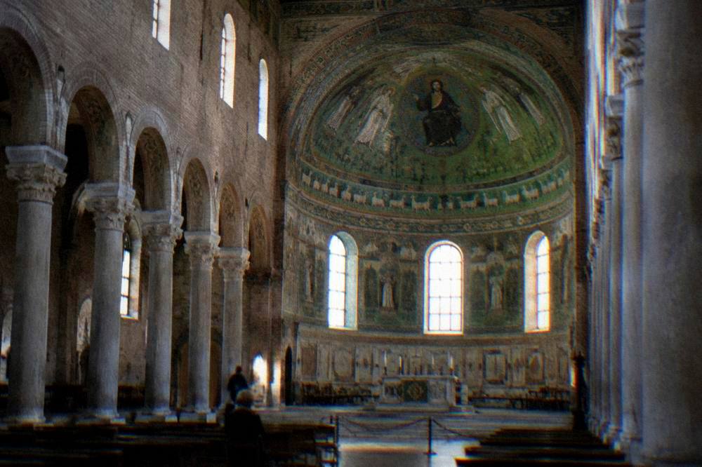 Sunlight falling across a gilded mosaic vault inside a Ravenna church