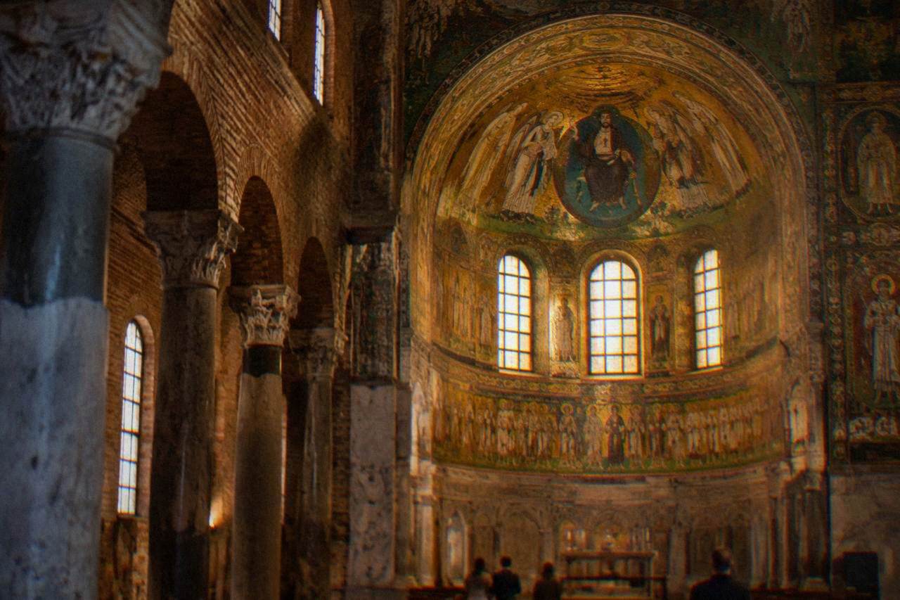 Golden Byzantine mosaics glowing inside an ancient brick church interior in Ravenna