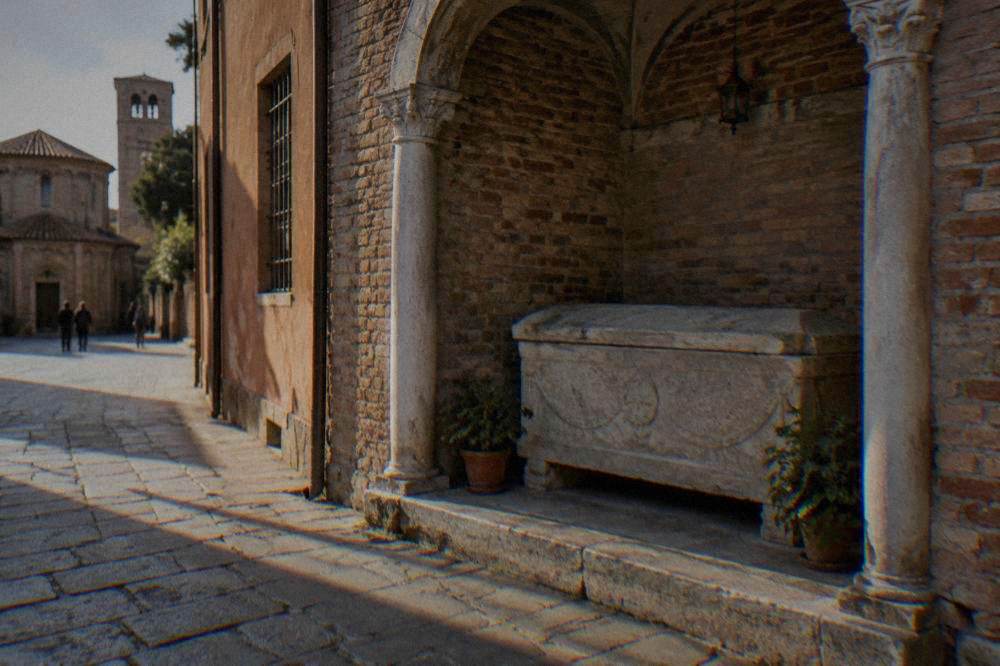 A simple stone sarcophagus in a quiet Ravenna street-side shrine