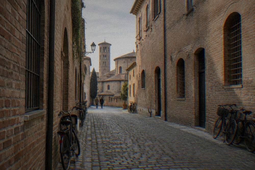 A narrow cobbled street in the historic centre of Ravenna lined with old brick buildings and bicycles