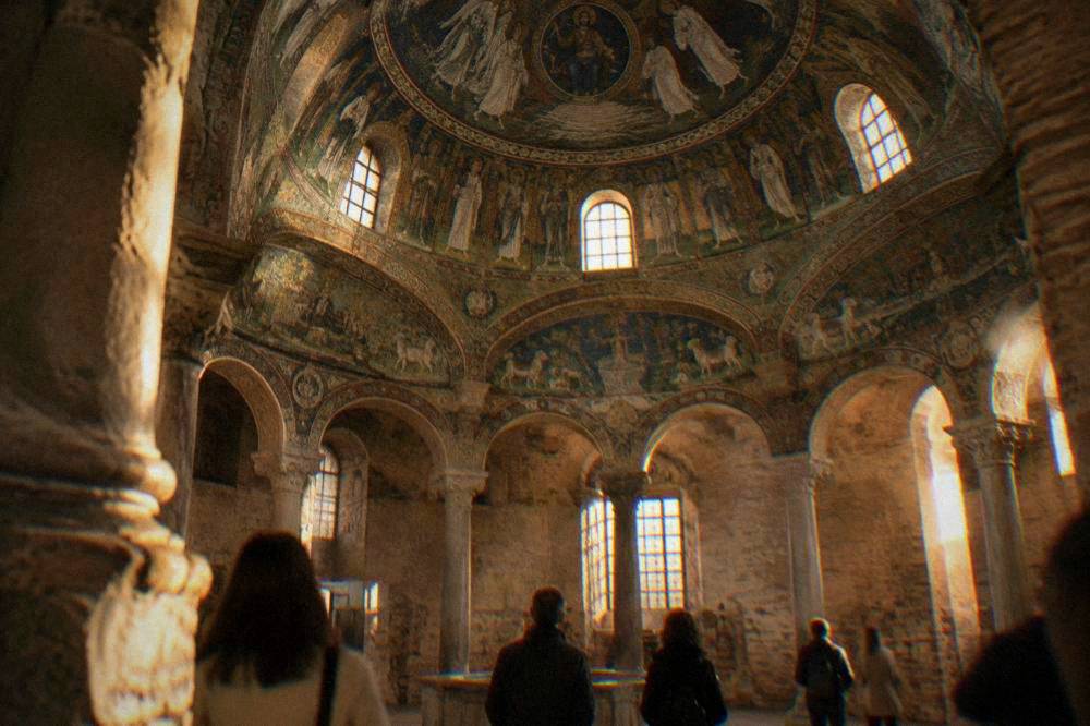 Visitors standing beneath the decorated dome of an early Christian baptistery in Ravenna